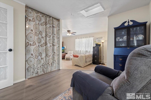 interior space with a textured ceiling, a skylight, and wood finished floors