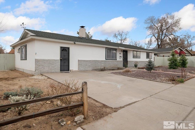 ranch-style home featuring stone siding, a chimney, and fence