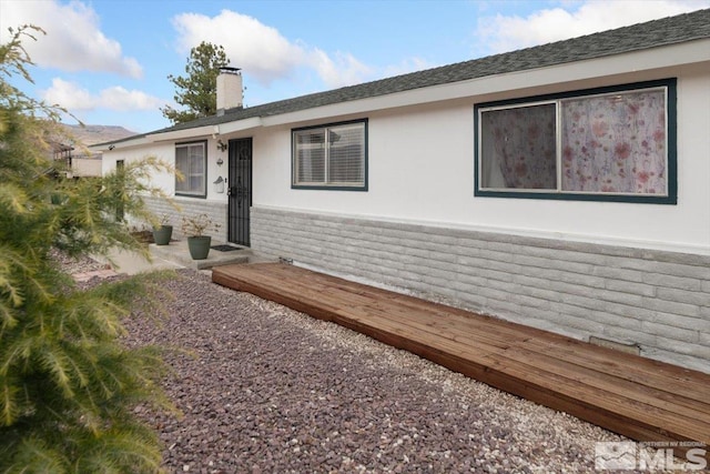 view of front facade with a chimney and stucco siding