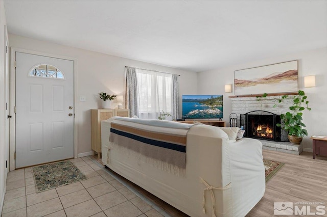 living room featuring a brick fireplace and baseboards