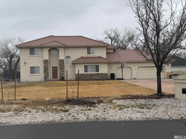 mediterranean / spanish home featuring a front yard, driveway, stucco siding, a garage, and stone siding