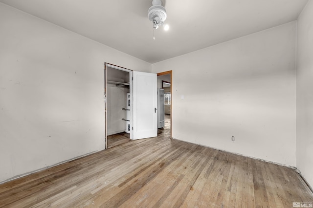 unfurnished bedroom featuring light wood-style floors, fridge, a ceiling fan, and a closet