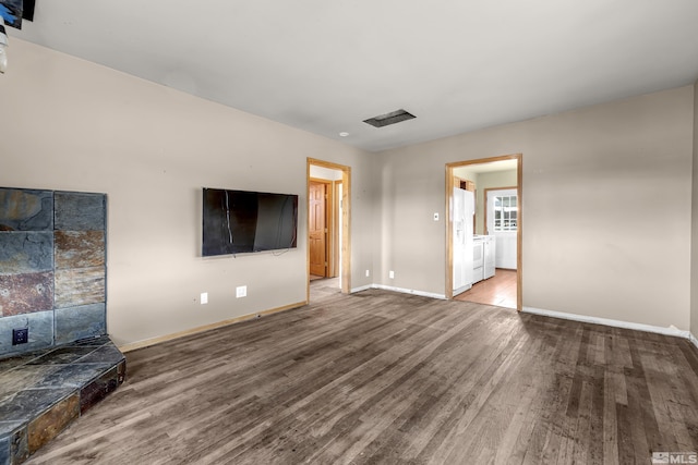 unfurnished living room with wood finished floors, visible vents, and baseboards