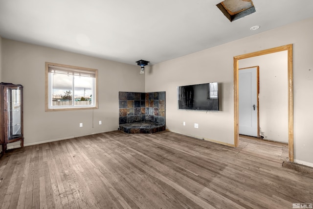 unfurnished living room featuring a fireplace, baseboards, and wood finished floors