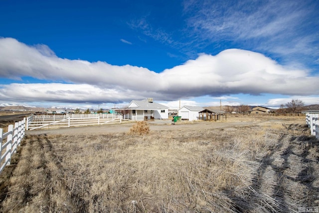 view of yard with fence and a rural view