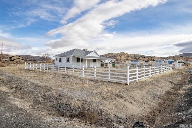 exterior space with a rural view, fence, and a mountain view