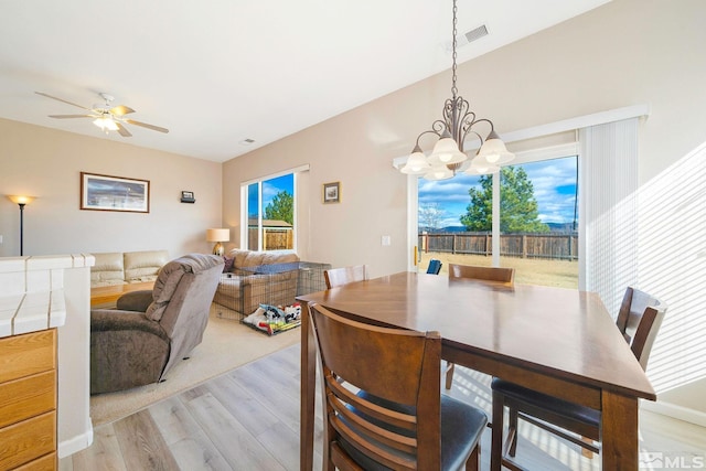 dining area with visible vents, light wood finished floors, and ceiling fan with notable chandelier