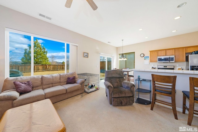 living room with ceiling fan with notable chandelier, light colored carpet, visible vents, and recessed lighting