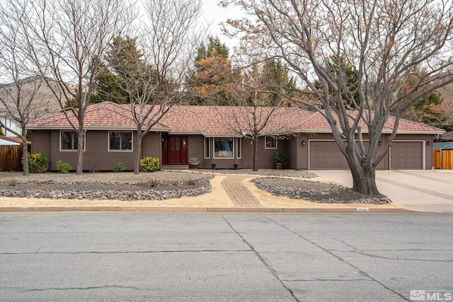 single story home featuring stucco siding, concrete driveway, fence, a garage, and a tiled roof