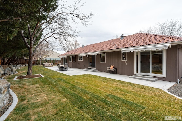 back of house featuring entry steps, a lawn, a tiled roof, fence, and a patio area