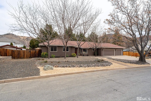 ranch-style house featuring a garage, fence, driveway, and a tiled roof