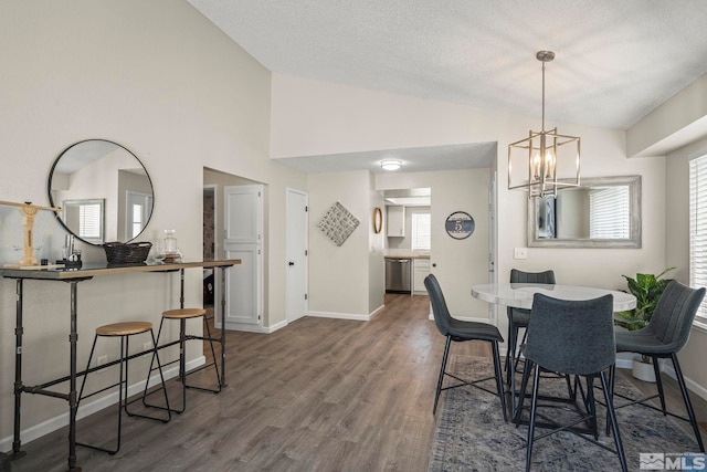 dining space with a wealth of natural light, an inviting chandelier, vaulted ceiling, wood finished floors, and baseboards