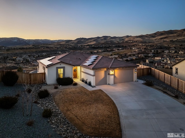 view of front facade featuring concrete driveway, fence, a mountain view, and stucco siding