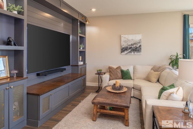 living room featuring dark wood-style floors, built in shelves, and baseboards