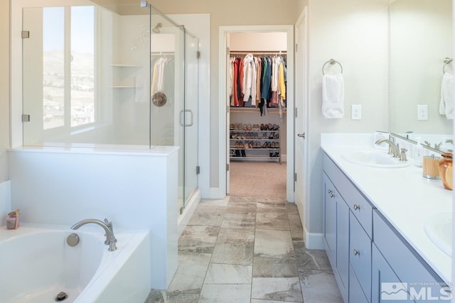 bathroom with double vanity, a stall shower, a bath, a spacious closet, and a sink