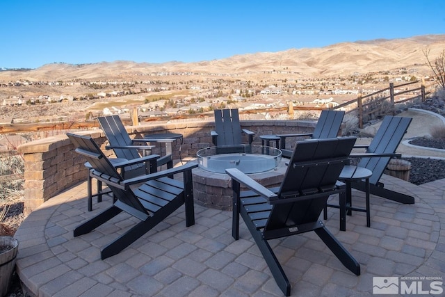 view of patio / terrace with an outdoor fire pit, a desert view, and a mountain view