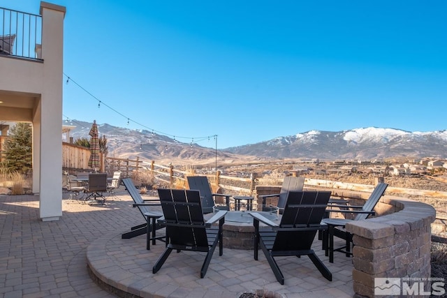 view of patio / terrace with an outdoor fire pit, fence, a mountain view, and outdoor dining area