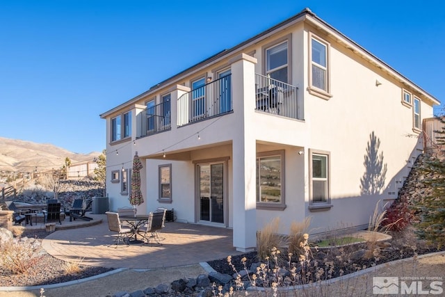 rear view of house with a patio area, a mountain view, and stucco siding