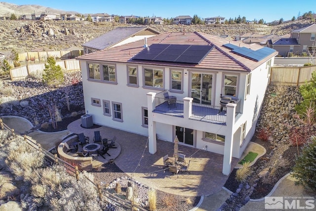 rear view of property with central AC unit, solar panels, a fenced backyard, a patio area, and stucco siding