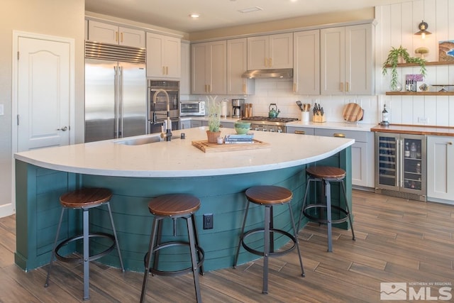 kitchen with a toaster, decorative backsplash, wine cooler, stainless steel built in refrigerator, and under cabinet range hood