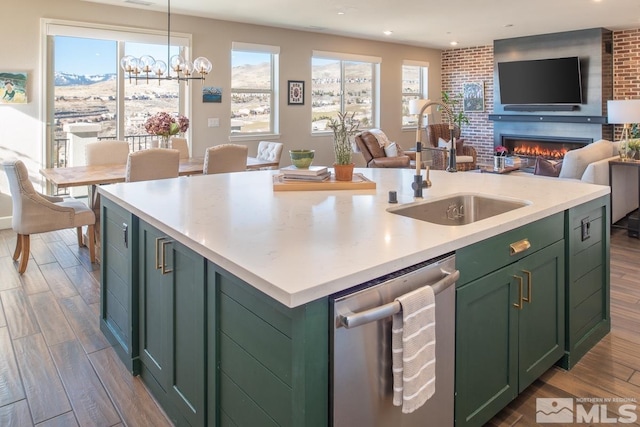 kitchen with a center island with sink, green cabinetry, dark wood-type flooring, stainless steel dishwasher, and a sink