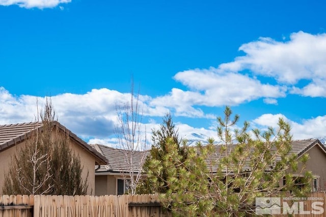 view of side of home featuring a tile roof, fence, and stucco siding