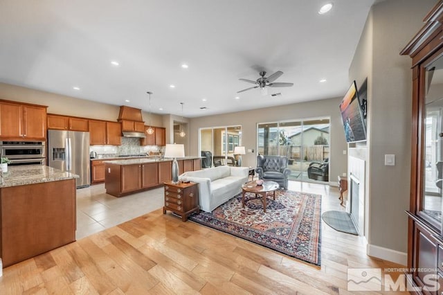 living room featuring light wood finished floors, visible vents, baseboards, a ceiling fan, and recessed lighting