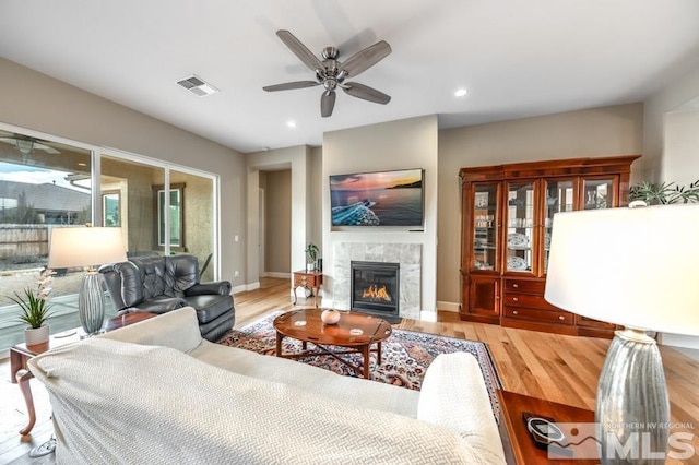 living area with light wood finished floors, baseboards, a fireplace, and visible vents