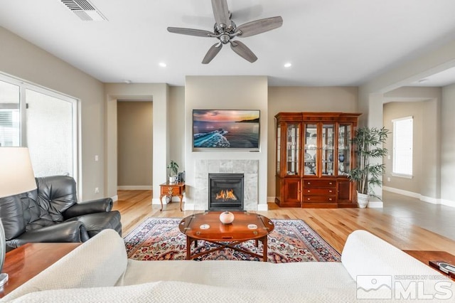 living room with baseboards, visible vents, wood finished floors, a fireplace, and recessed lighting