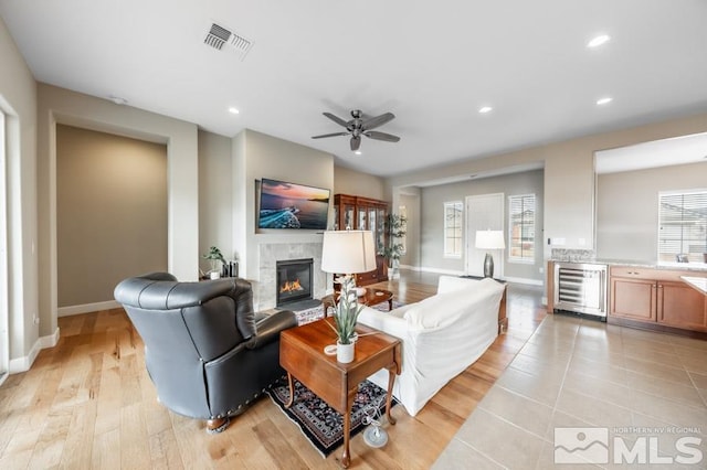 living room featuring beverage cooler, visible vents, a wealth of natural light, and a glass covered fireplace