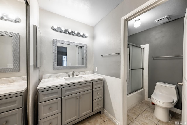 bathroom featuring baseboards, toilet, tile patterned flooring, combined bath / shower with glass door, and vanity