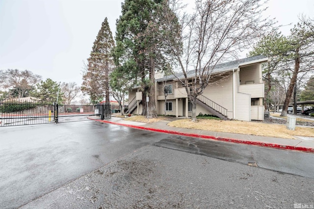 exterior space with a gated entry, stairway, curbs, a gate, and sidewalks