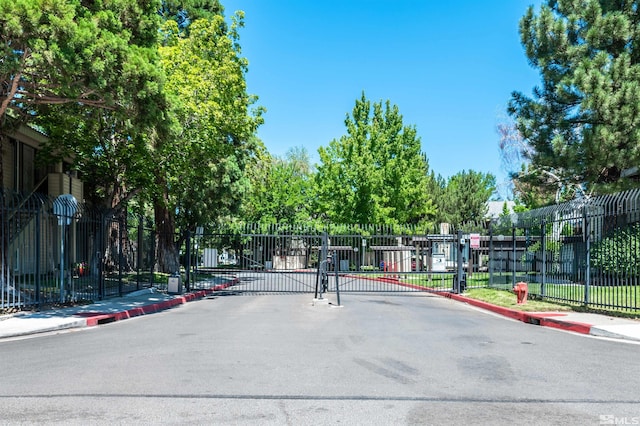 view of street with sidewalks, a gate, a gated entry, and curbs