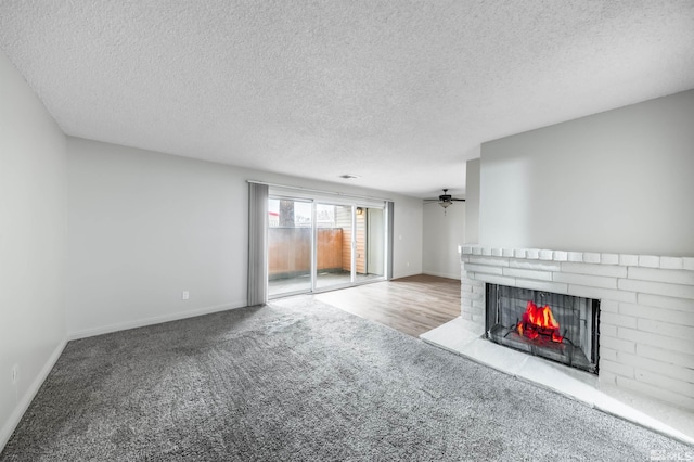 unfurnished living room with a brick fireplace, carpet flooring, a ceiling fan, and baseboards