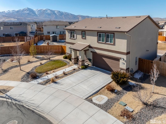 view of front of property featuring concrete driveway, a residential view, fence, a mountain view, and stucco siding