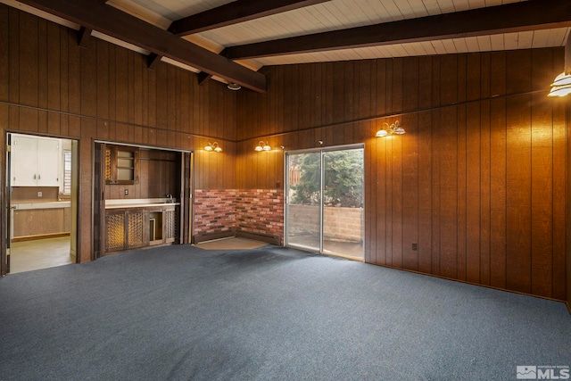 spare room featuring carpet, wooden walls, high vaulted ceiling, and beamed ceiling