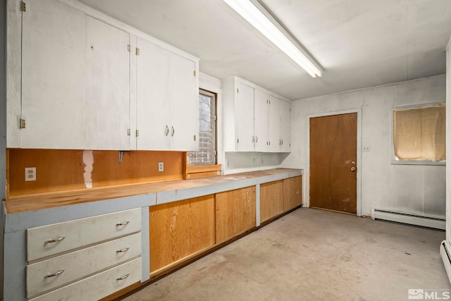 kitchen featuring a baseboard heating unit, white cabinets, concrete flooring, and light countertops