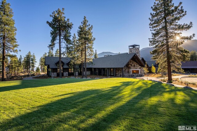 rear view of house featuring a yard and stone siding