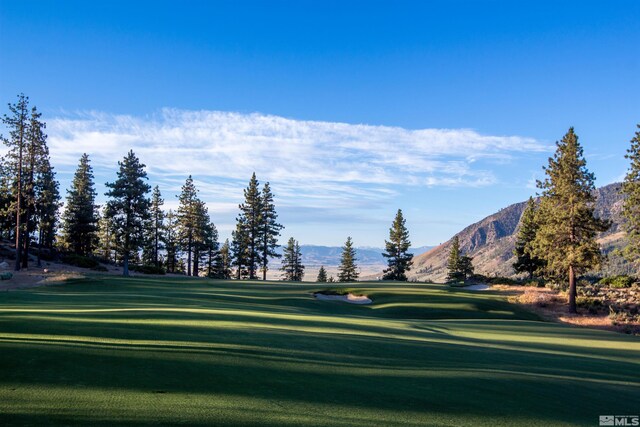 view of community featuring a yard, view of golf course, and a mountain view