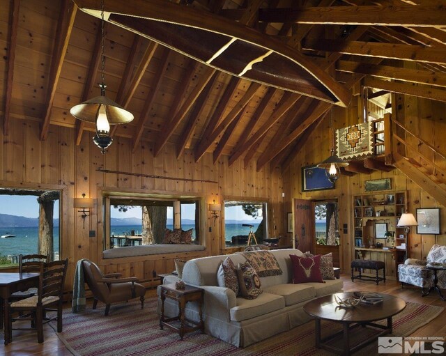 living area featuring beamed ceiling, wood walls, wood finished floors, and a healthy amount of sunlight