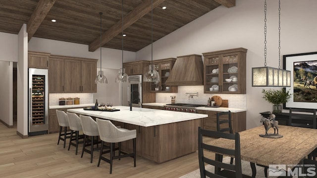 kitchen featuring beverage cooler, light countertops, a center island with sink, and light wood-style flooring