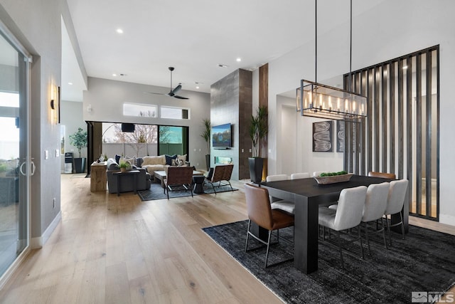 dining space featuring recessed lighting, a towering ceiling, baseboards, a ceiling fan, and light wood-type flooring