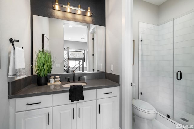 bathroom featuring a shower stall, toilet, and vanity