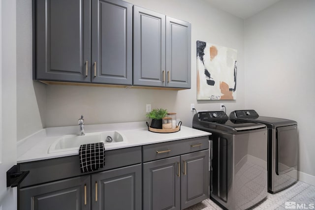 laundry room featuring washer and clothes dryer, cabinet space, light tile patterned flooring, a sink, and baseboards