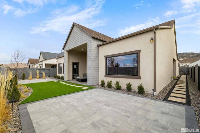 back of property with a patio area, a lawn, a fenced backyard, and stucco siding