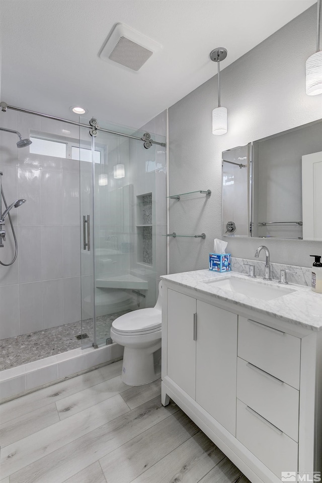 full bathroom featuring toilet, a shower stall, visible vents, and vanity