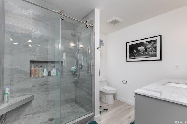 full bathroom featuring toilet, wood finished floors, vanity, visible vents, and a stall shower