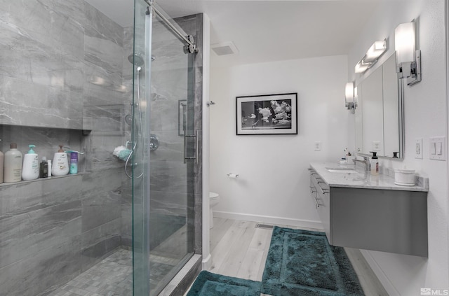 bathroom featuring baseboards, toilet, wood finished floors, vanity, and a shower stall