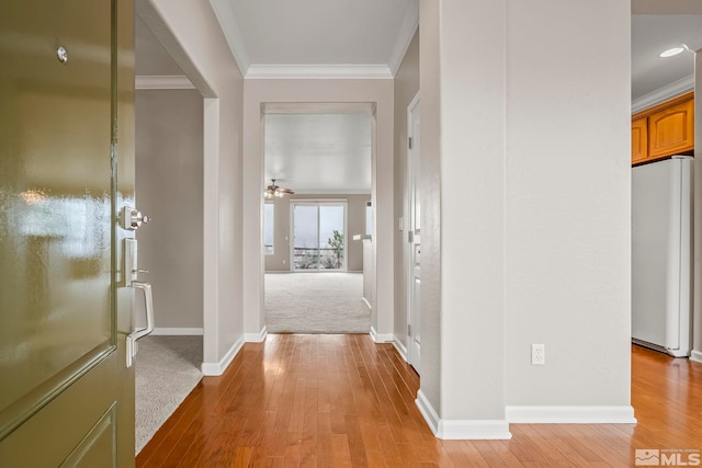 hall featuring ornamental molding, light wood-style flooring, and baseboards