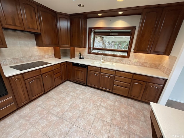 kitchen featuring light countertops, tasteful backsplash, a sink, and black electric cooktop